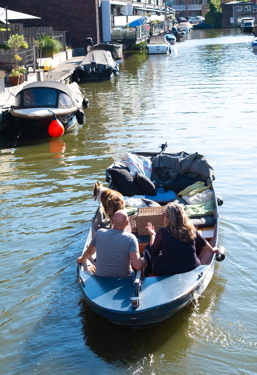 A couple and their dog travelling along a Haarlem canal by boat