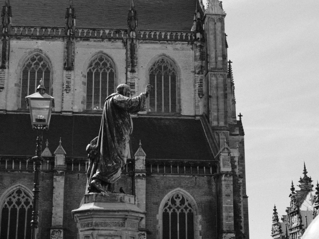 A statue and the Grote Kerk photographed in black and white