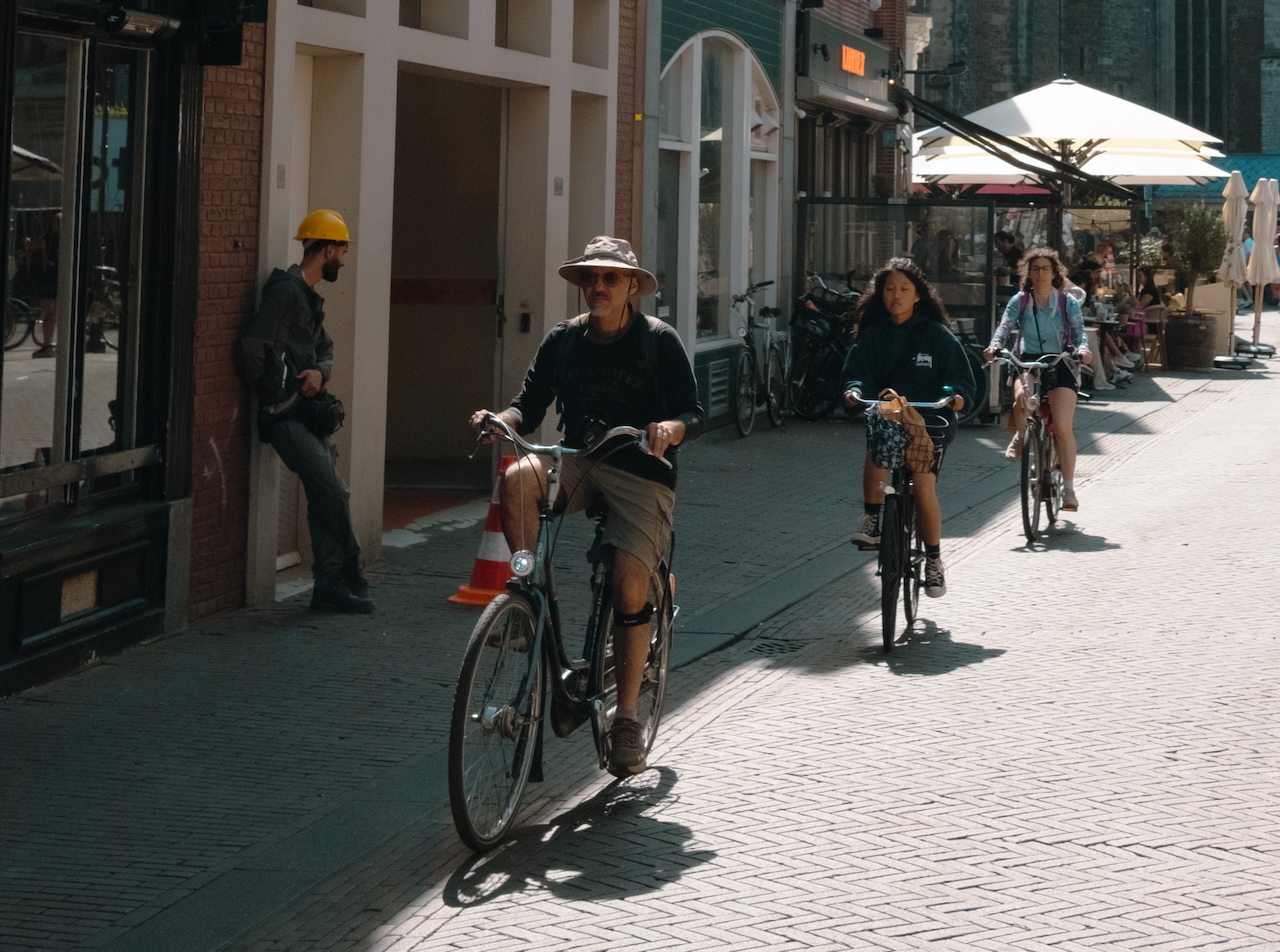 Three cyclists riding through a sunlit street in Haarlem