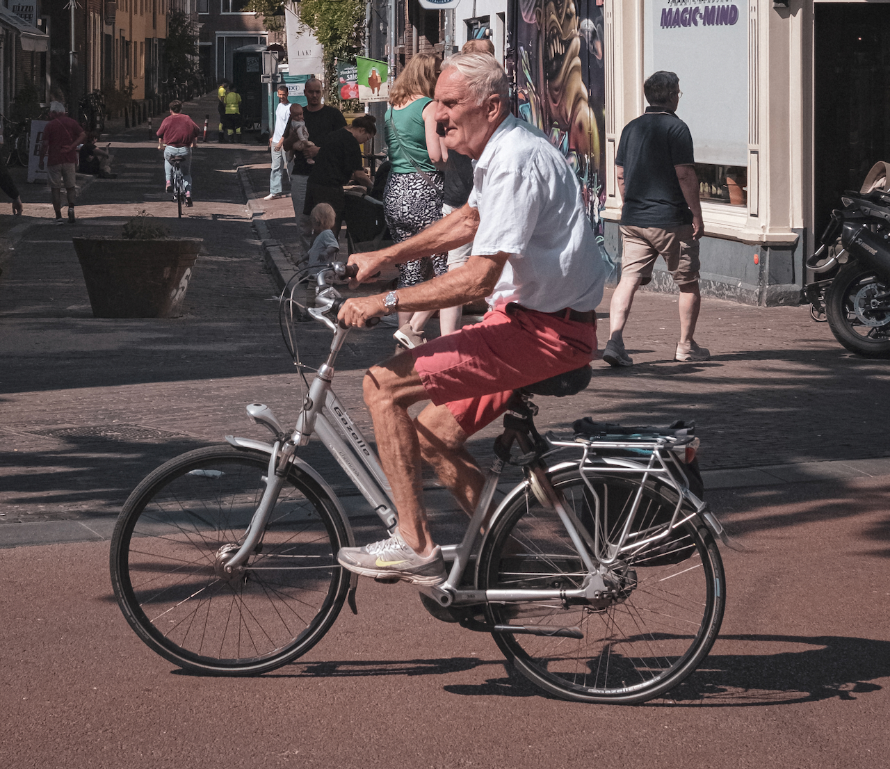 An older man cycling through a busy Utrecht street