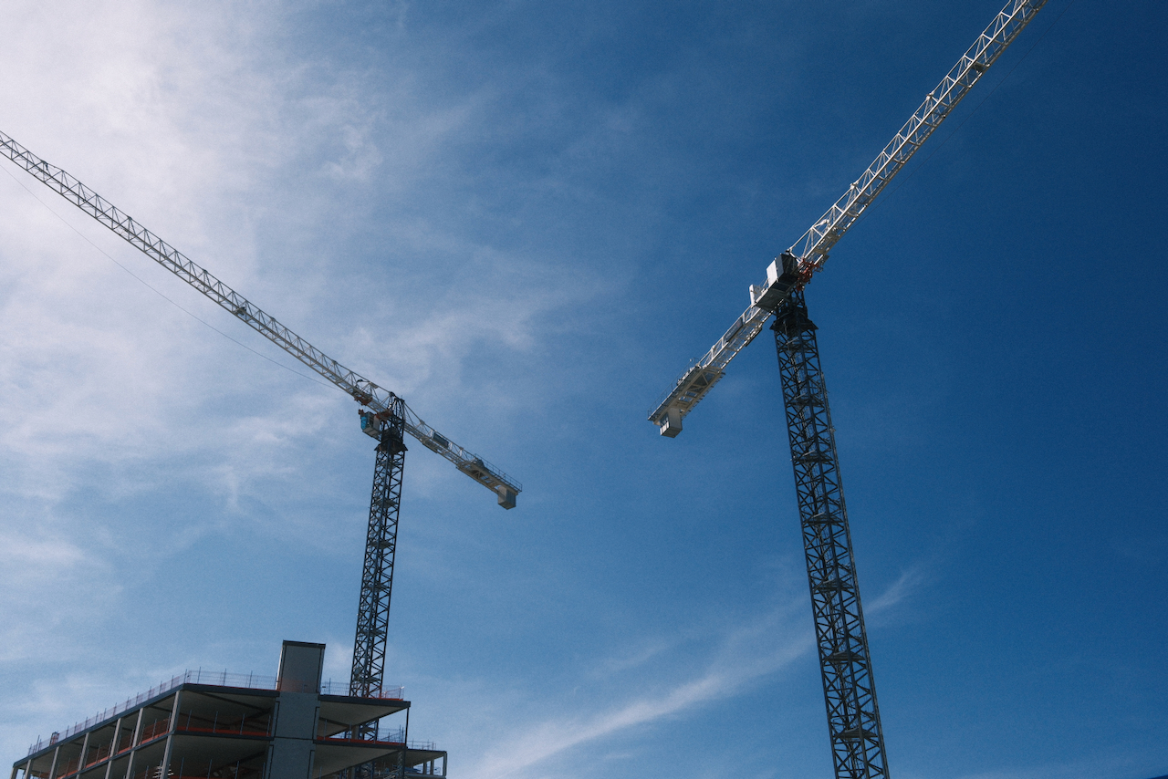 Two construction cranes crossing a blue Utrecht sky