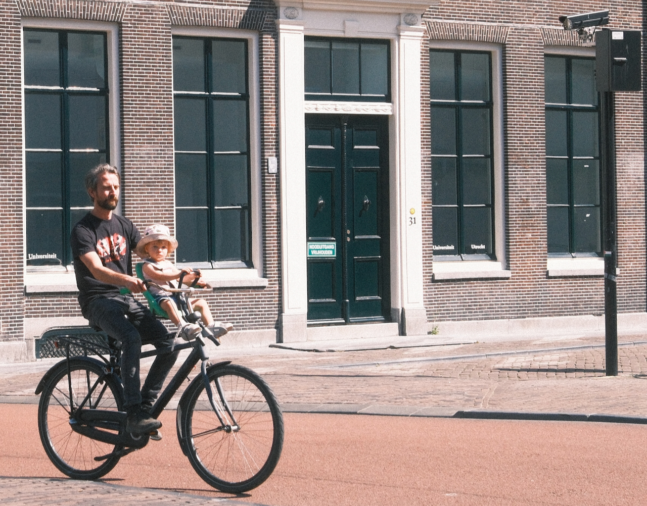A father cycling with a young child through Utrecht