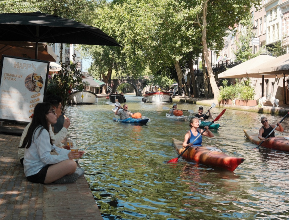 Kayakers and people relaxing beside the Oudegracht in Utrecht