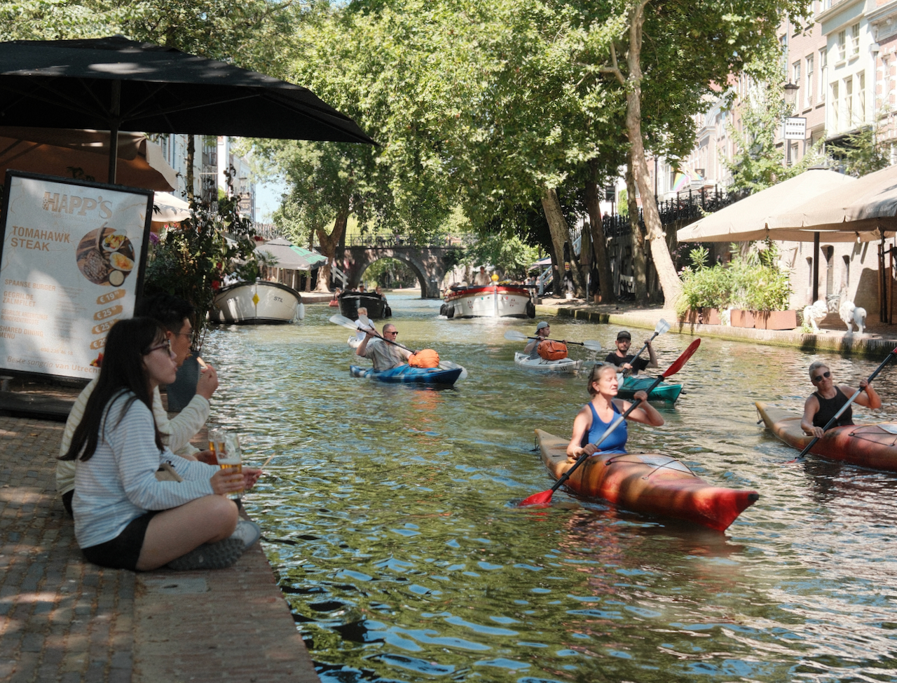 Kayakers and people relaxing beside the Oudegracht in Utrecht