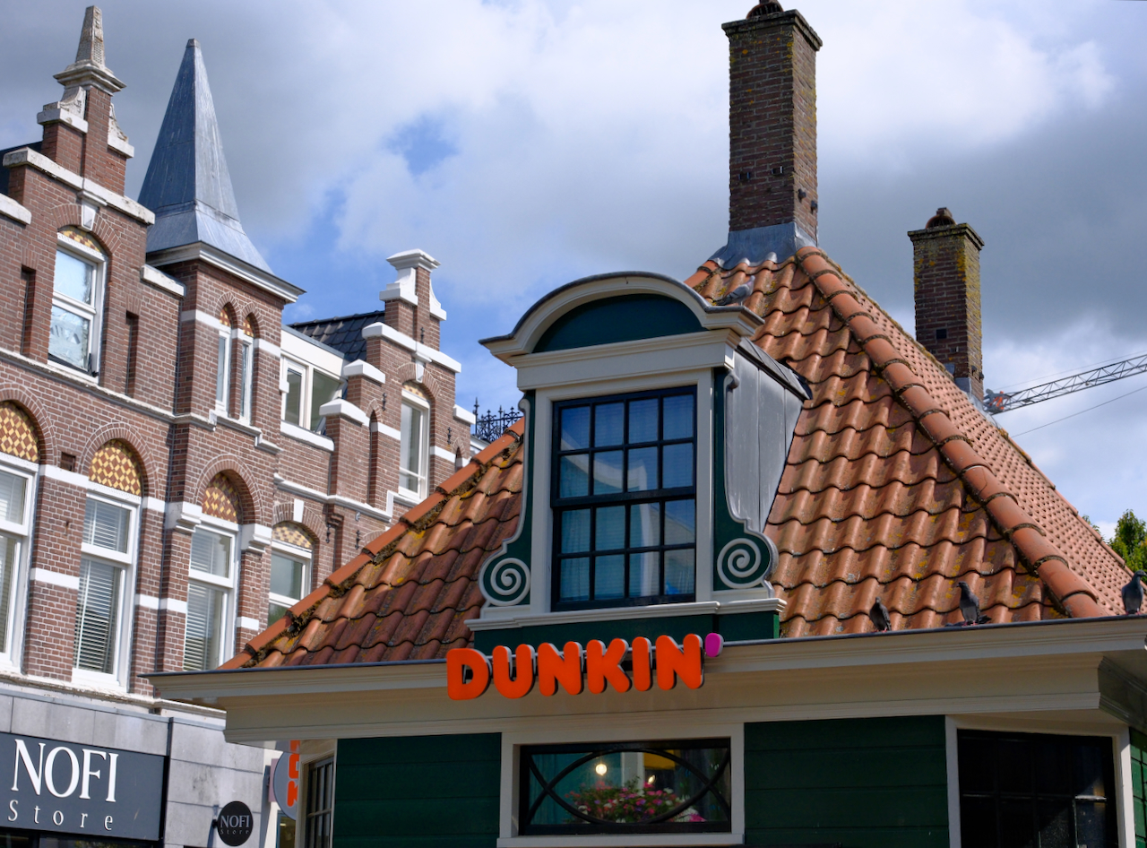 A traditional green gable rising above a Dunkin storefront