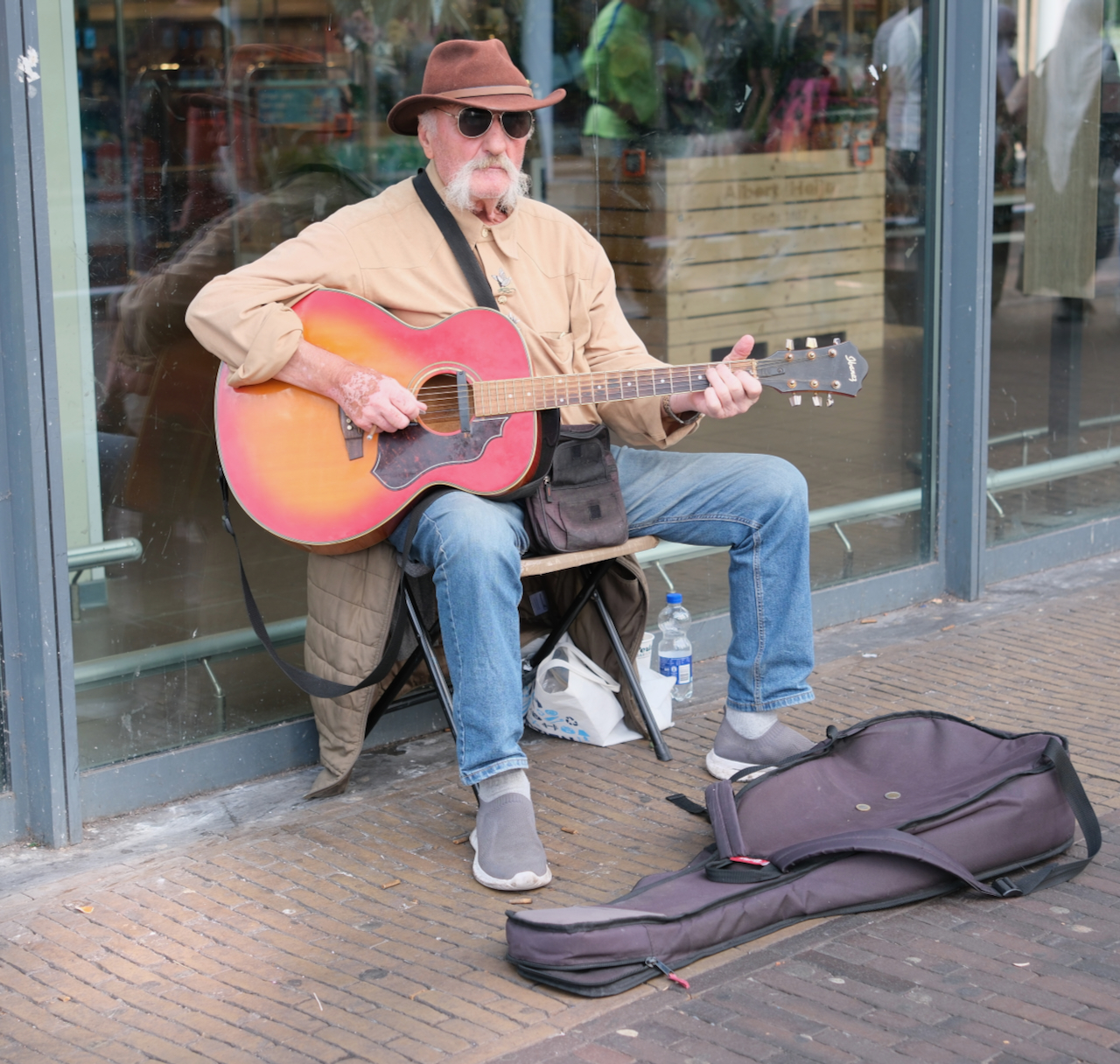 A street musician playing a red acoustic guitar in Zaandam