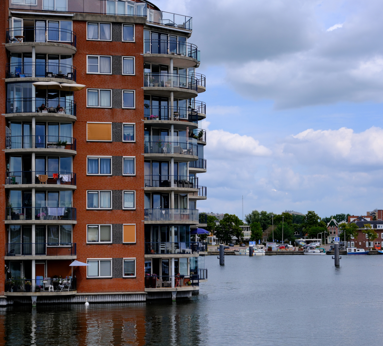 Waterside apartments and boats beneath broad summer clouds